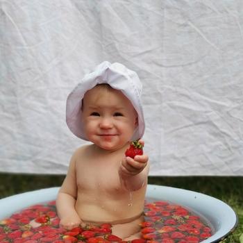 A Cute Baby Girl on a Basin with Strawberries