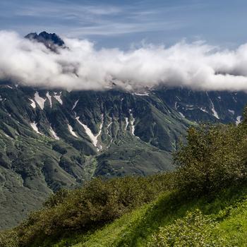 Green Grass Field and Mountain Under White Clouds During Day